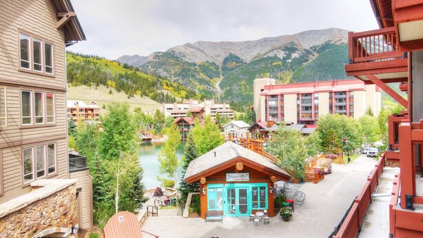 A mountain resort with a riverside view, wooden buildings, and a small cafe.