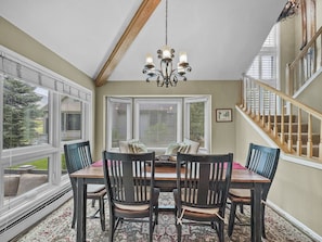 Enjoy meals in this dining area with a table and four chairs, a chandelier, and large windows.