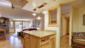 A spacious kitchen with wooden cabinets, a granite countertop, and pendant lighting.