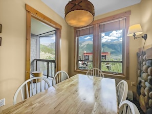 Enjoy meals with a view of the surrounding mountains from this dining area with a wooden table and large windows.