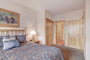 Une chambre à coucher avec un lit, une table de chevet, une lampe, un tableau et des portes en bois.