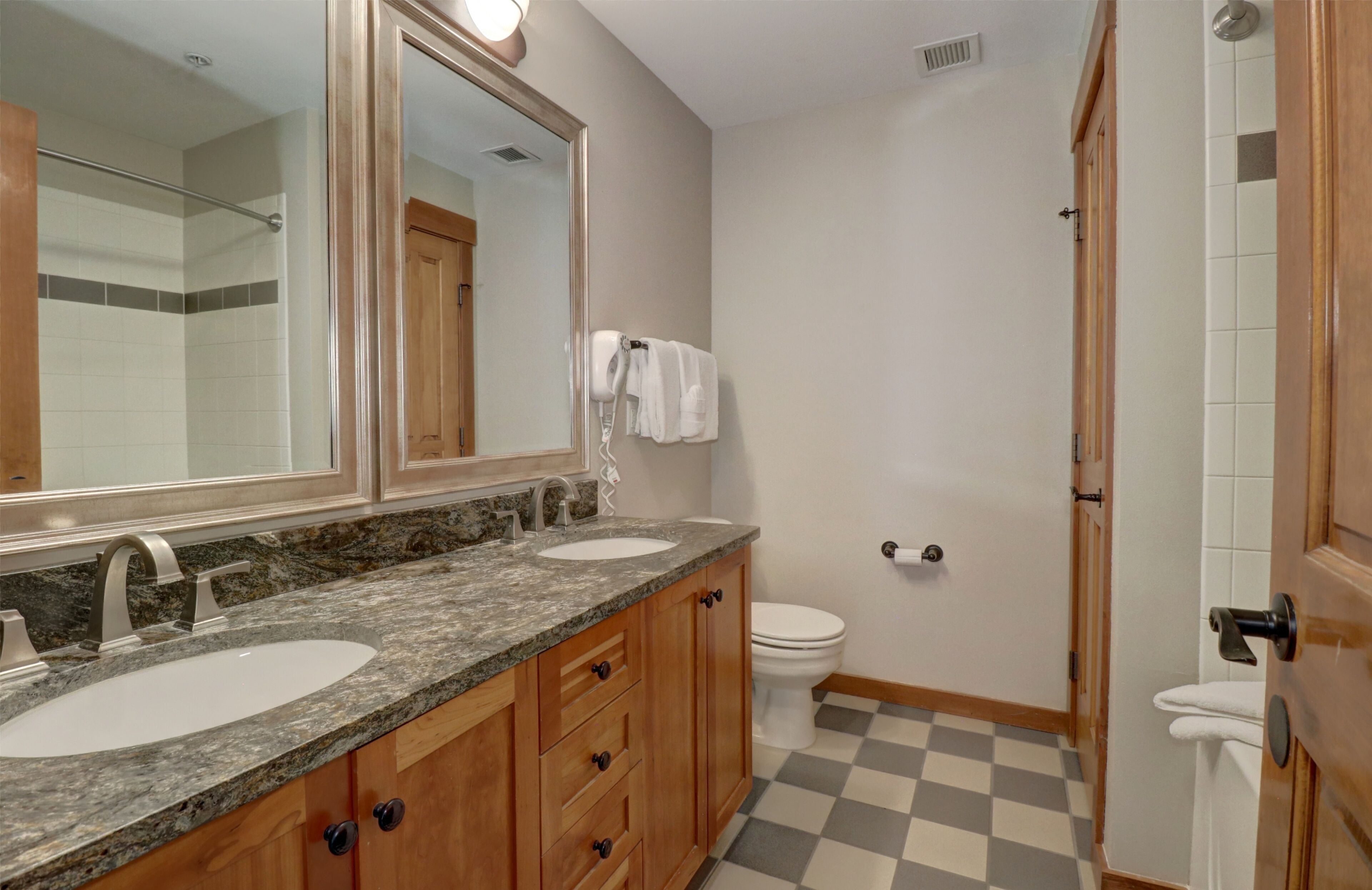A bathroom with two sinks, a large mirror, and a shower area.