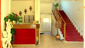 A hotel reception area with a red counter, a staircase with red carpet, and a decorative ceiling light. - Hotel Krone (Alsfeld)