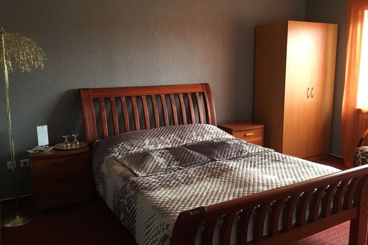 Makuuhuoneessa on puinen sänky, yöpöytä, vaatekaappi ja lattiavalaisin.