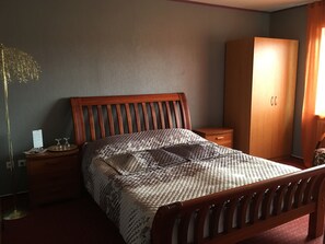 Une chambre à coucher avec un lit en bois, une table de chevet, une armoire et une lampe sur pied.