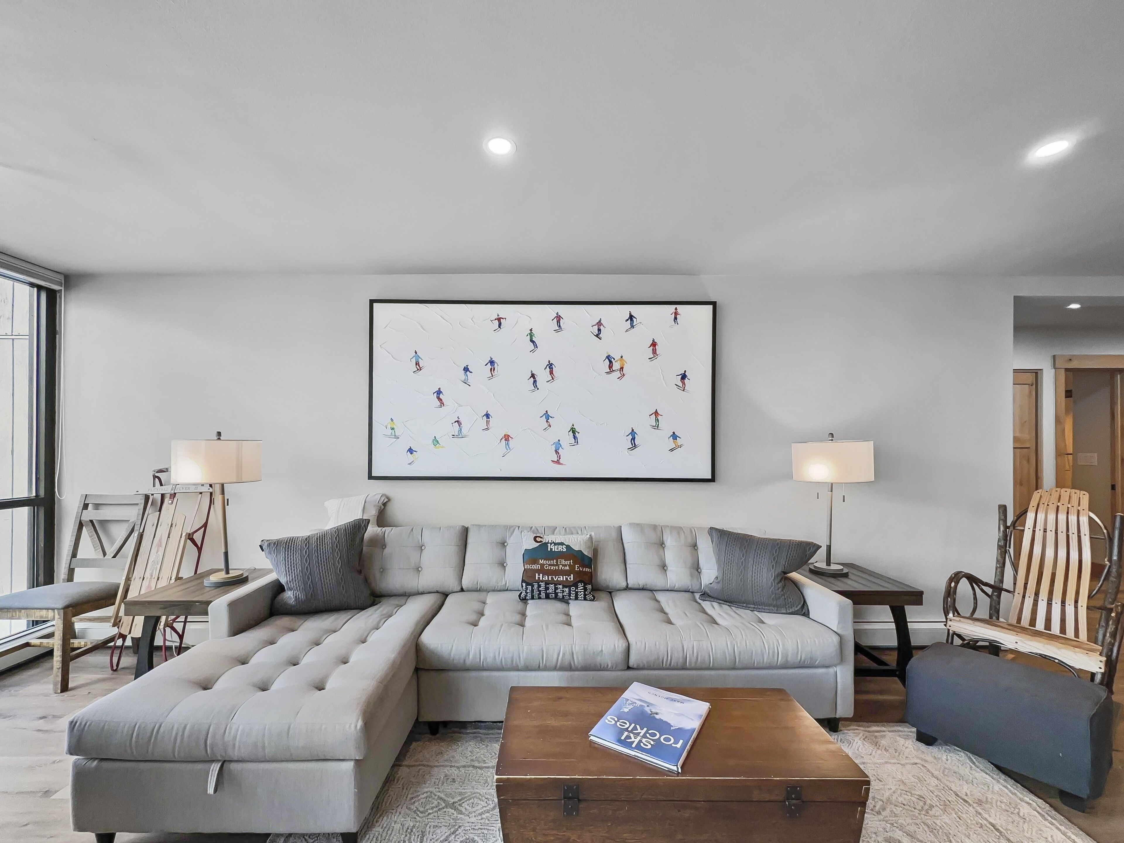 A modern living room with a sectional sofa, a coffee table, and a framed artwork on the wall.