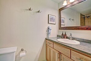 A bathroom with a white sink, wooden cabinets, a mirror, a hairdryer, and two framed pictures on the wall. - CM112H Copper Mtn Inn Studio Studio Bedroom 1Bathroom Hotel Room (Copper Mountain)