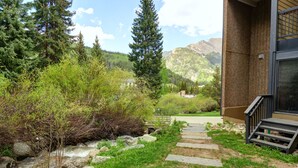 A stone staircase leading to a building with a glass door, surrounded by greenery and a mountain view. - CM112H Copper Mtn Inn Studio Studio Bedroom 1Bathroom Hotel Room (Copper Mountain)