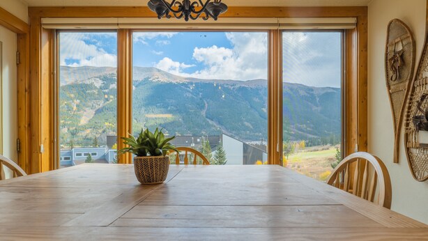 Ein Esstisch mit Blick auf Berge durch große Fenster.