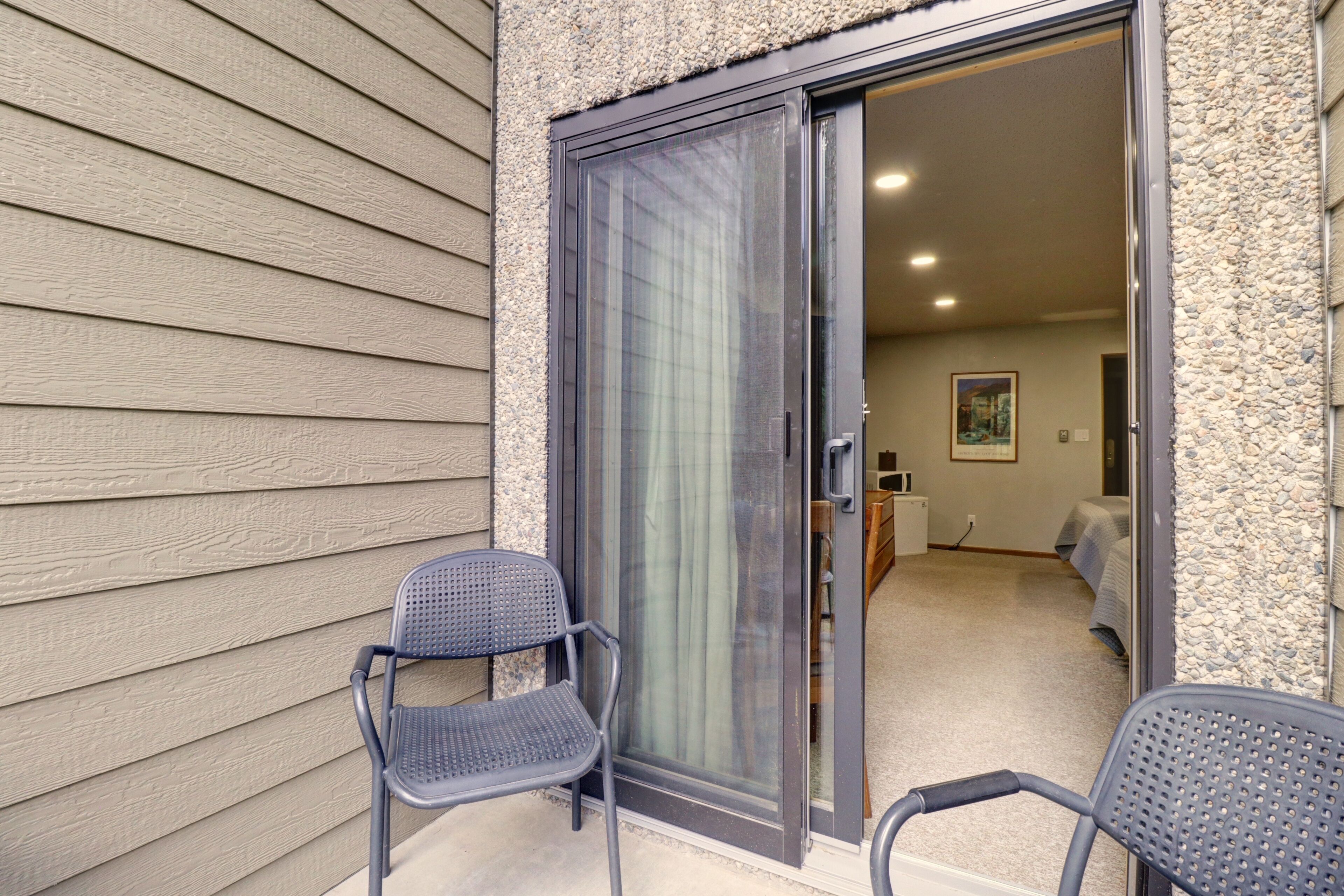 A room with a sliding glass door leading to a bedroom, a small table, and a chair.