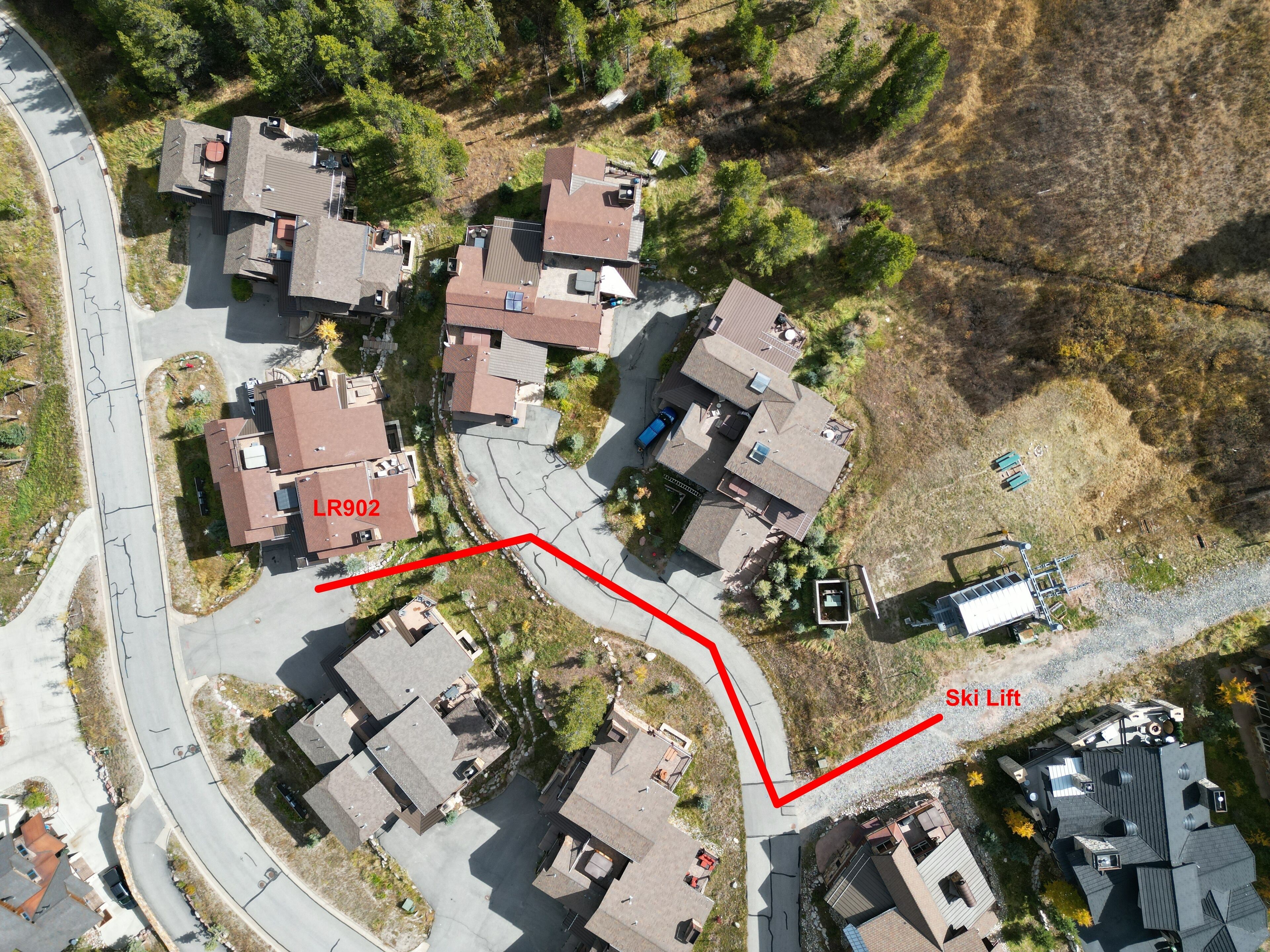 An aerial view of a residential area with houses, a ski lift, and a winding road.