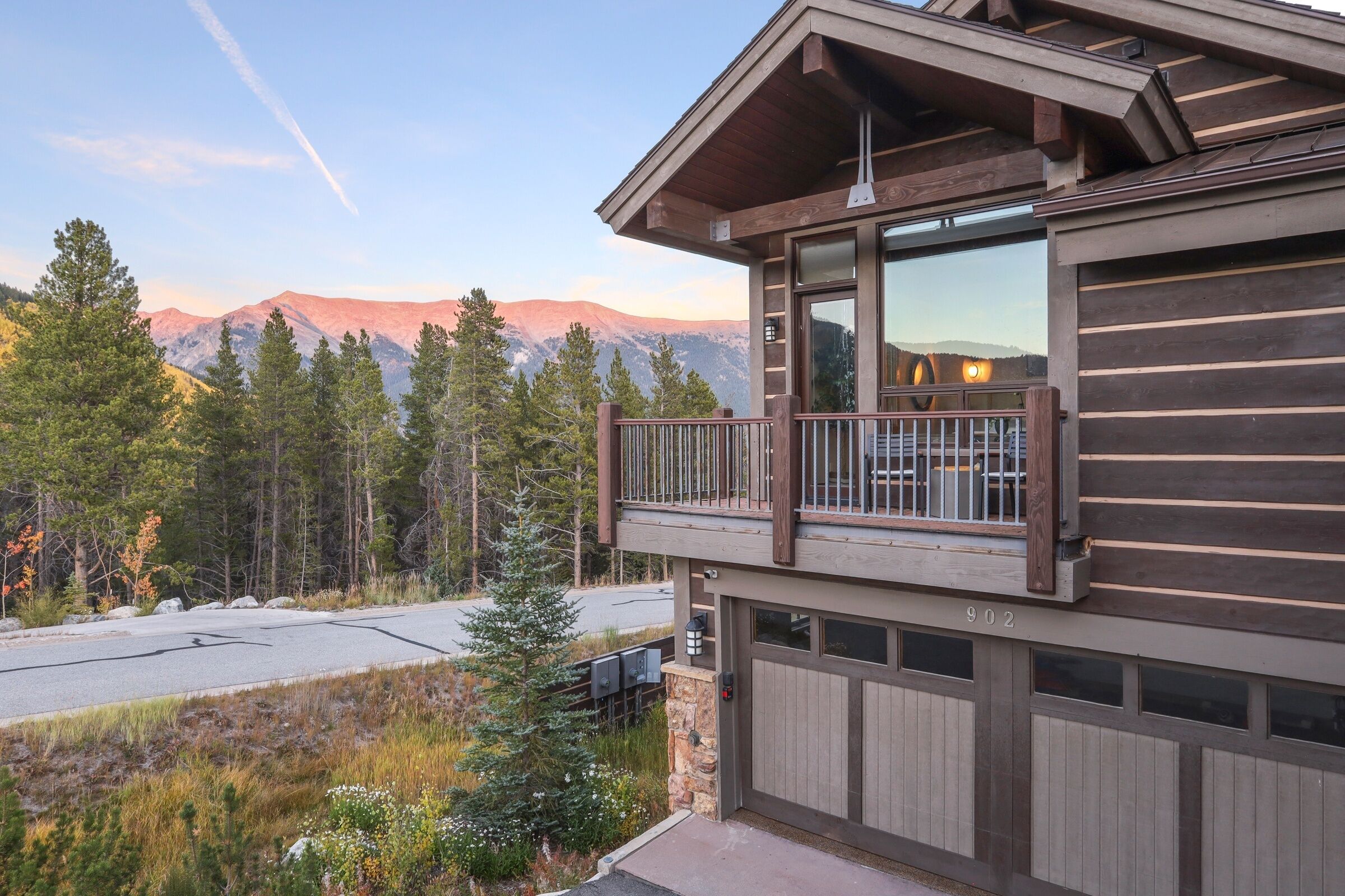 Eine moderne Blockhütte mit einem Balkon mit Blick auf eine gebirgige Landschaft.