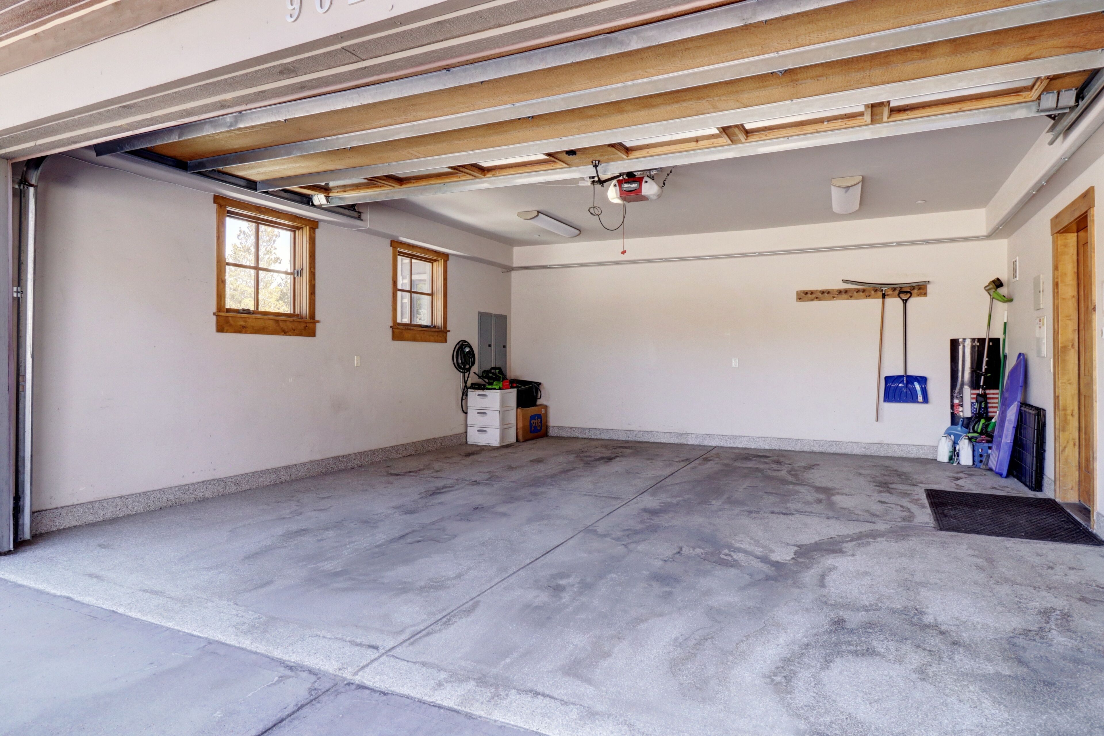 Un garage avec un sol en béton, des poutres en bois, un ventilateur de plafond et une fenêtre.