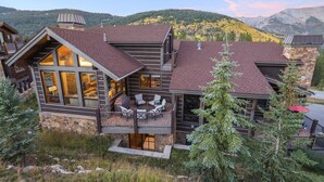 Una casa moderna de dos pisos con balcón, ventanas amplias y cimientos de piedra.