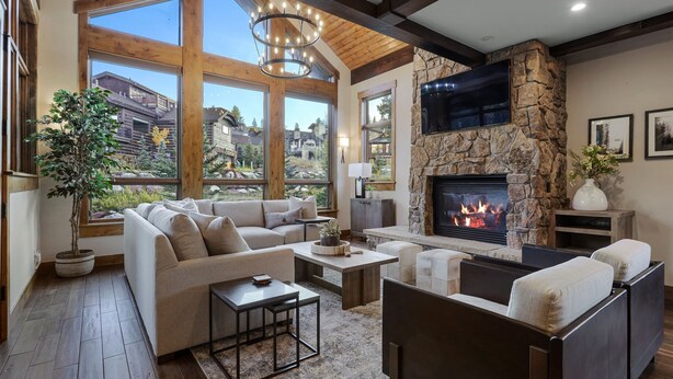 Un salón espacioso con chimenea de piedra, ventanas amplias y una zona de estar acogedora.