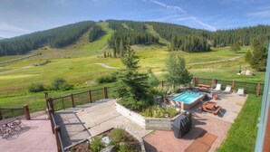 Un espace piscine doté d’un jacuzzi, de chaises longues et offrant une vue sur un paysage montagneux.