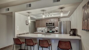A modern kitchen with a central island, stainless steel appliances, and bar stools. - 241c Mountain Side 2br 2ba 2 Bedroom Condo by RedAwning (Frisco)