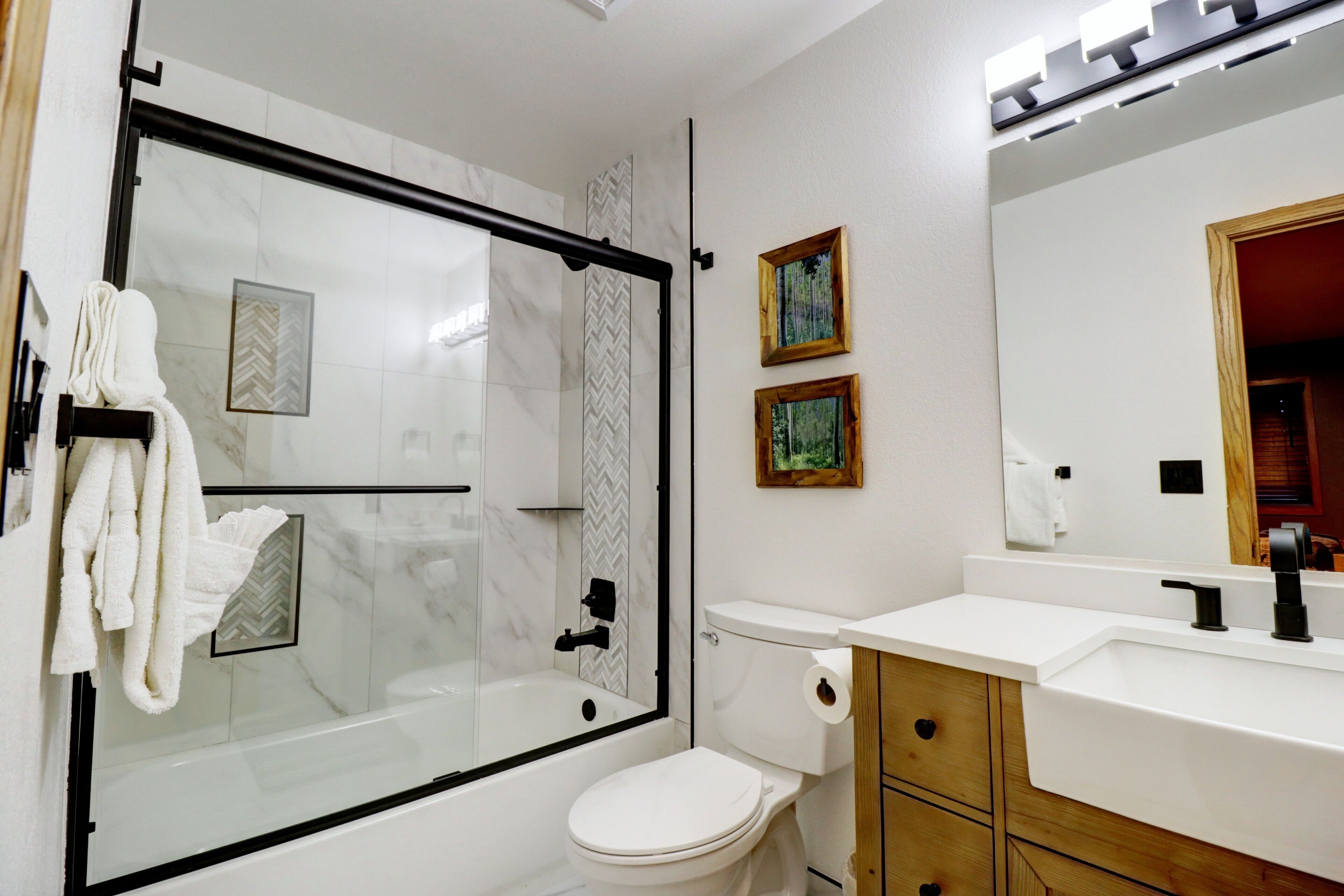 A modern bathroom with a glass-enclosed shower, a white toilet, and a vanity with a mirror.