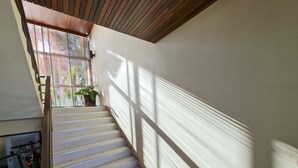A staircase with white steps leading to a landing, a potted plant on the landing, and a bicycle parked on the left.