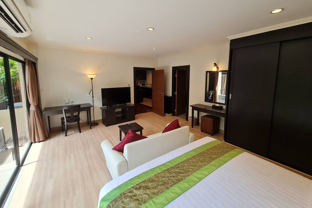 Une chambre d’hôtel avec un grand lit, une télévision, un bureau et un coin repas.