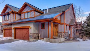 A two-story house with a stone foundation, wooden siding, and a metal roof.