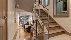 A modern interior with a staircase, wooden flooring, and a dining area with a table and chairs.