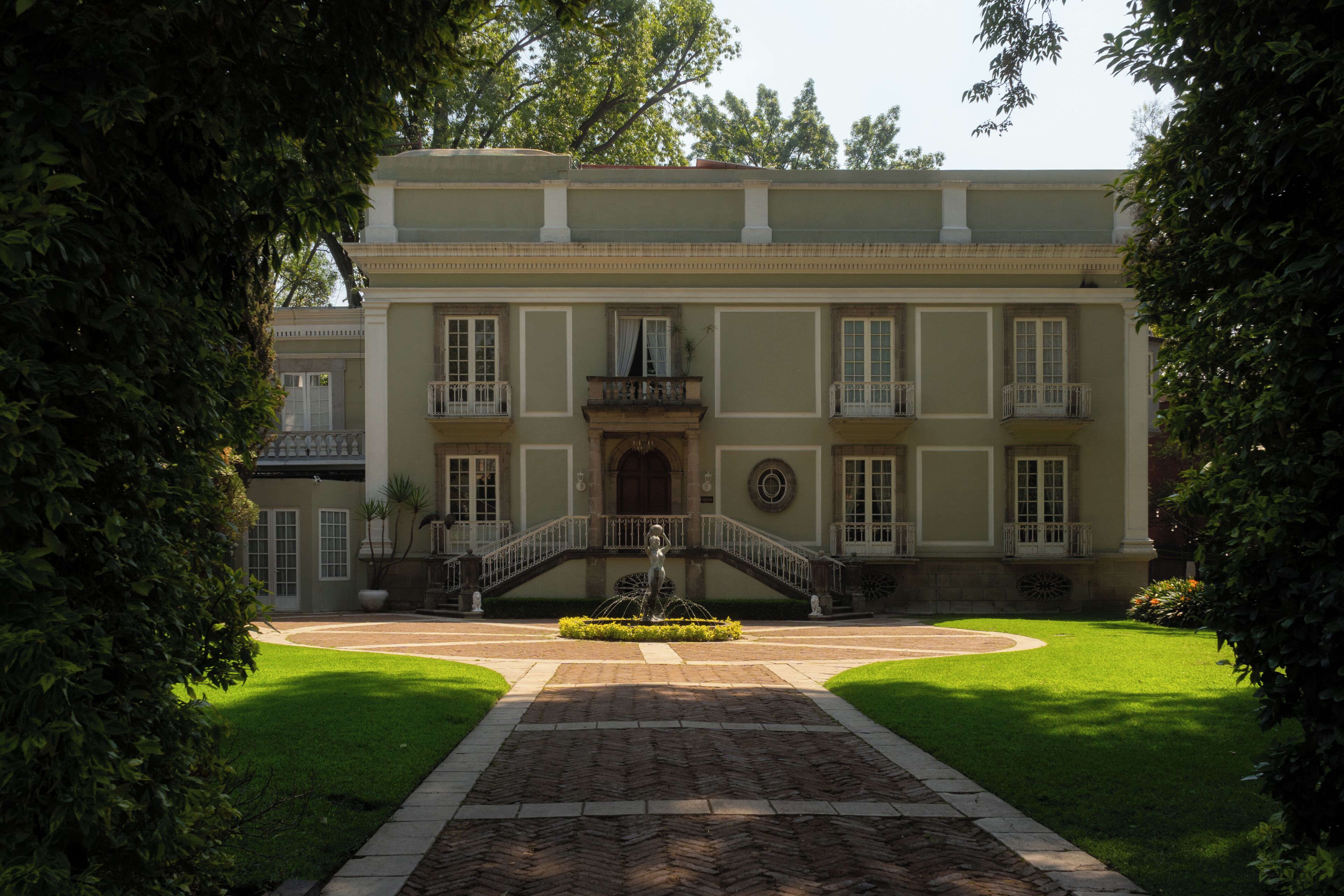 A stately building with a central entrance, a fountain, and a symmetrical facade.