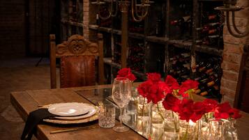 Una mesa de comedor de madera dispuesta con platos, vasos y rosas rojas.