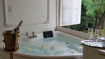 A bathtub with a champagne bottle, glasses, and flowers.