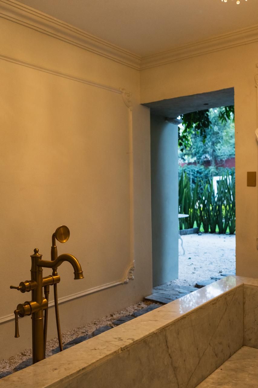 A bathroom with a marble sink and a gold faucet.
