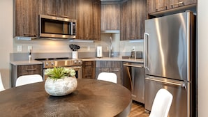 Een moderne keuken met houten kastjes, roestvrijstalen apparatuur en een centraal eiland met een plant.