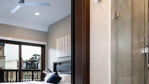 Een moderne hotelkamer met een groot bed, een plafondventilator en een douchecabine van glas.