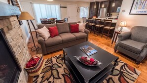 A cozy living room with a fireplace, a sofa, a coffee table, and a dining area with chairs and a table.