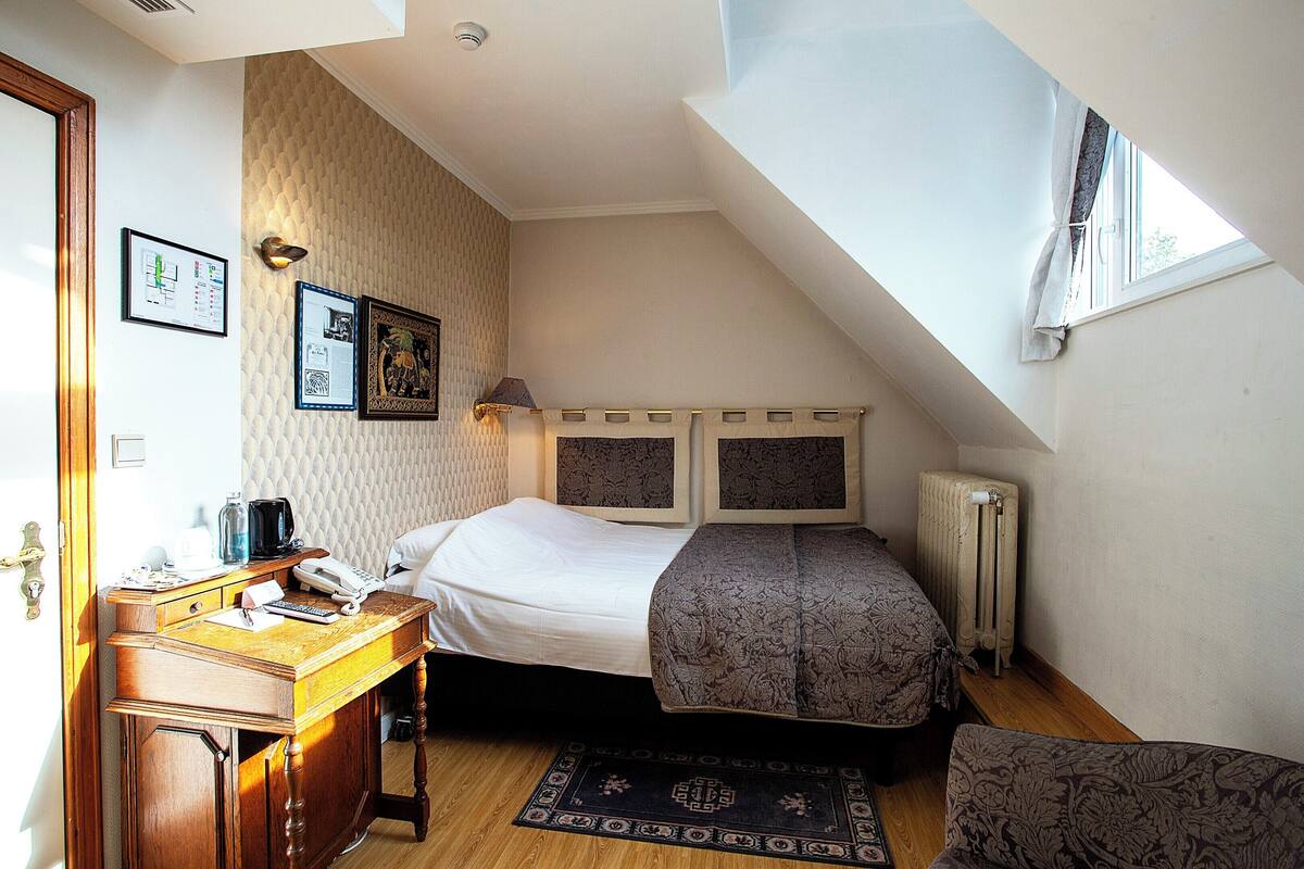 Quarto com cama, escrivaninha e radiador.