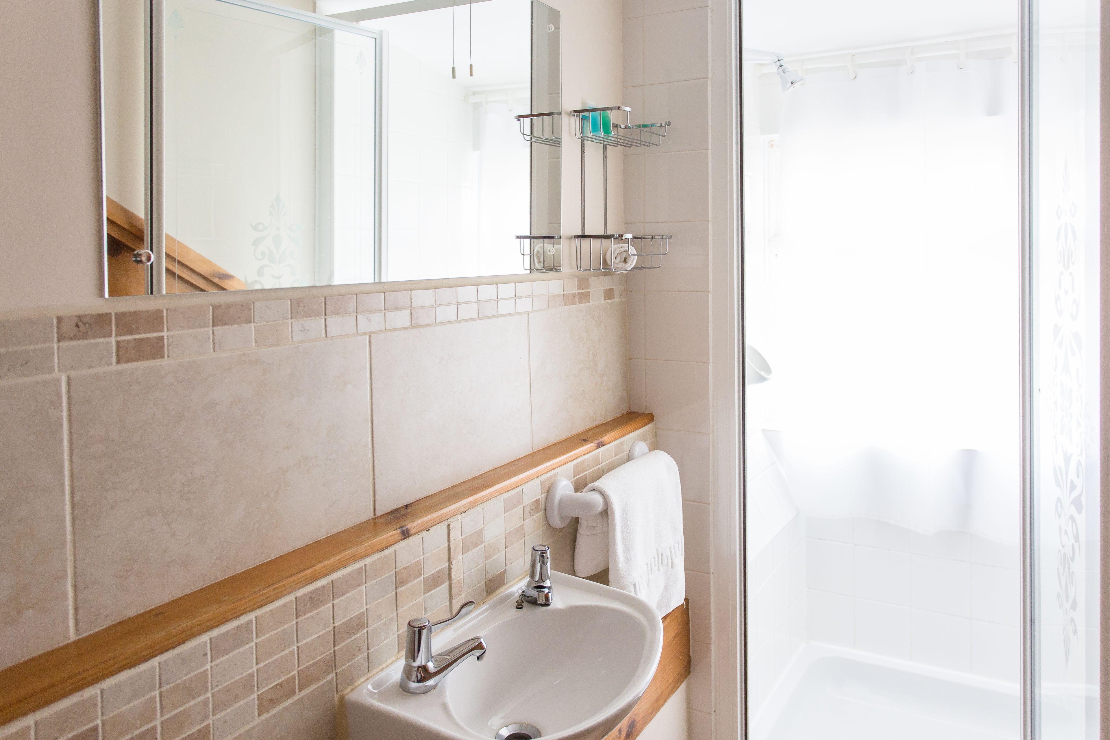 Un baño con lavamanos, espejo y ducha.