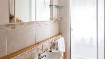 Un baño con lavamanos, espejo y ducha.