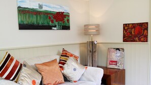 A living room with a white sofa, wooden coffee table, and paintings on the walls. - Greenbanks Hotel (Dereham)