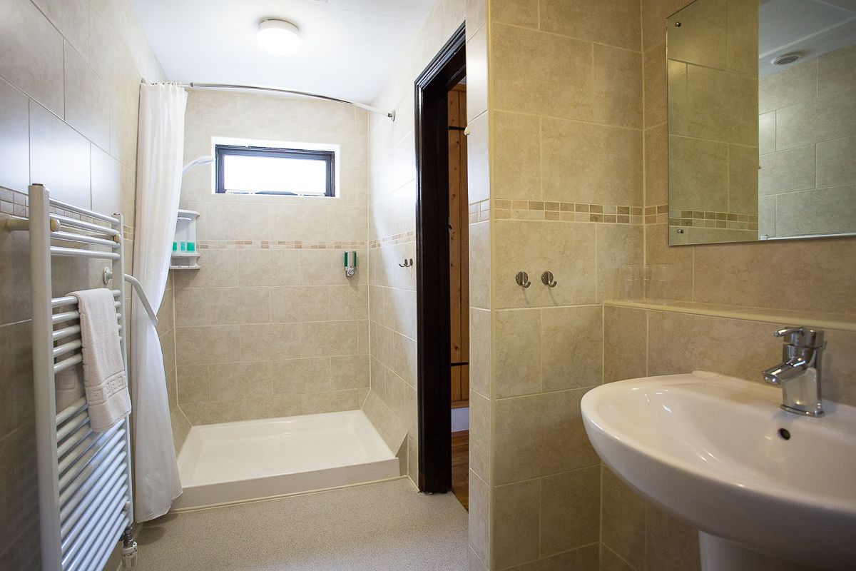 A bathroom with a bathtub, a sink, a window, and a shower area.