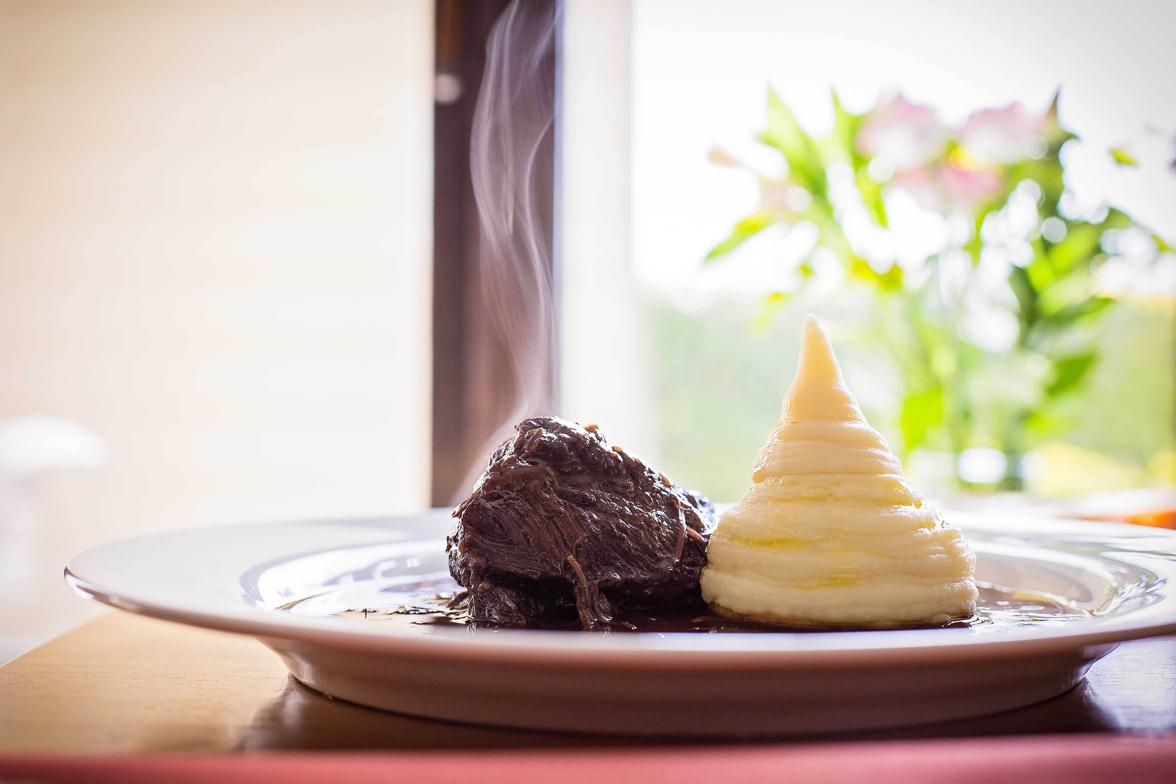 Un postre en un plato, con una ventana al fondo.