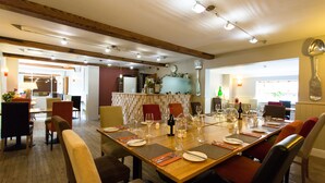 A dining area with a long wooden table set for a meal, surrounded by chairs with cushioned seats. - Greenbanks Hotel (Dereham)