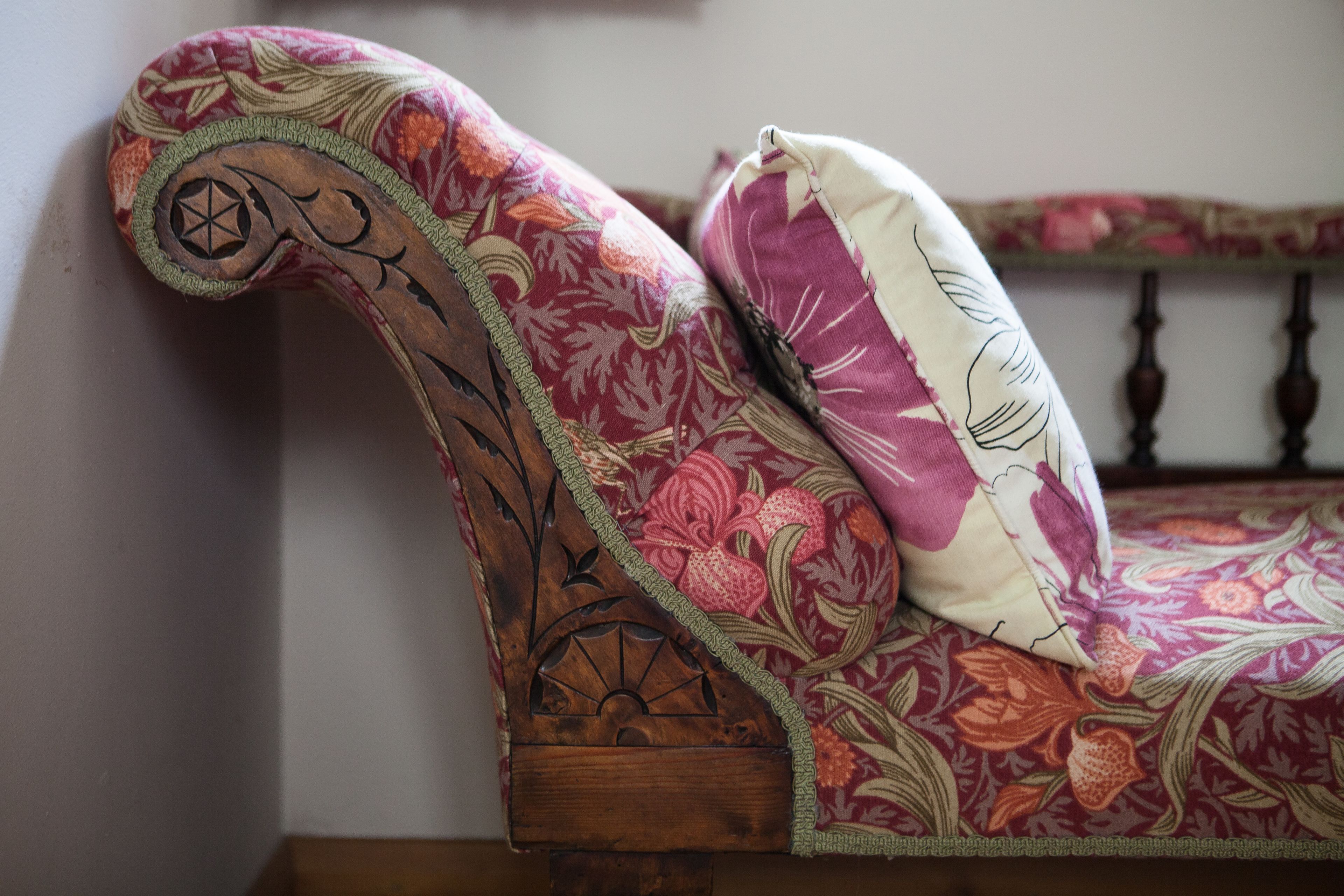 A wooden bed frame with floral upholstery and a decorative headboard.