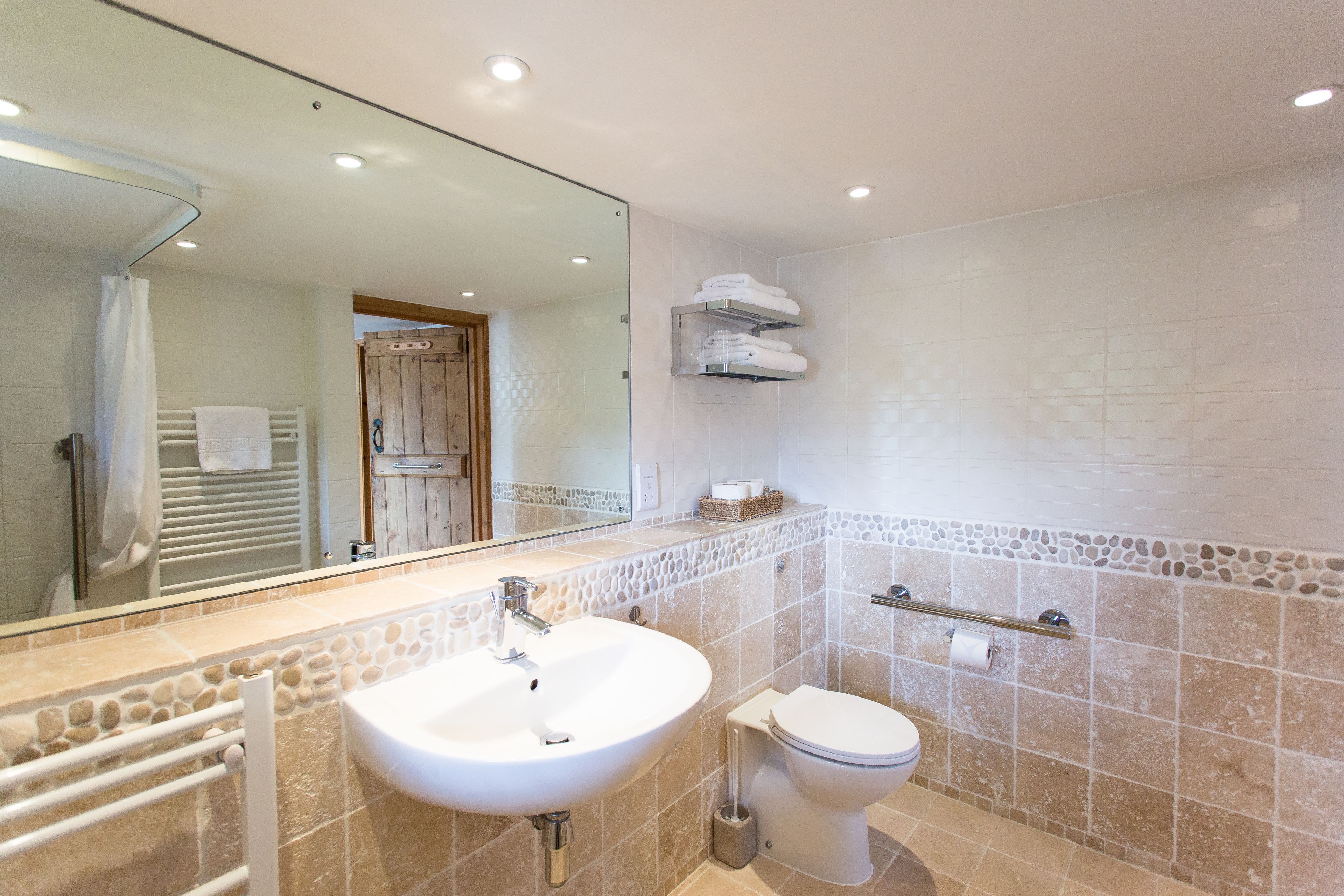 A bathroom with a white sink, toilet, and a mirror above the sink.