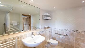 A bathroom with a white sink, toilet, and a mirror above the sink.