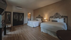 Een hotelkamer met twee bedden, een bureau, een stoel, een televisie en een kledingkast.