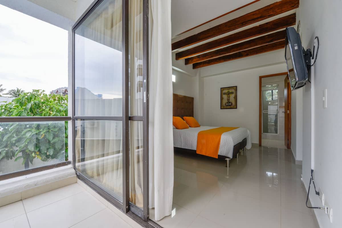 Un dormitorio con una cama, televisión y ventana con cortinas.
