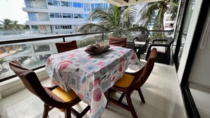 Un balcón con una mesa dispuesta para dos personas, con mantel estampado y dos sillas con cojines.