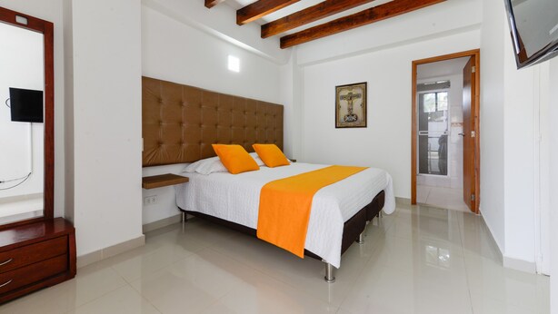 Un dormitorio con cama, vigas de madera, televisor y un cuadro en la pared.