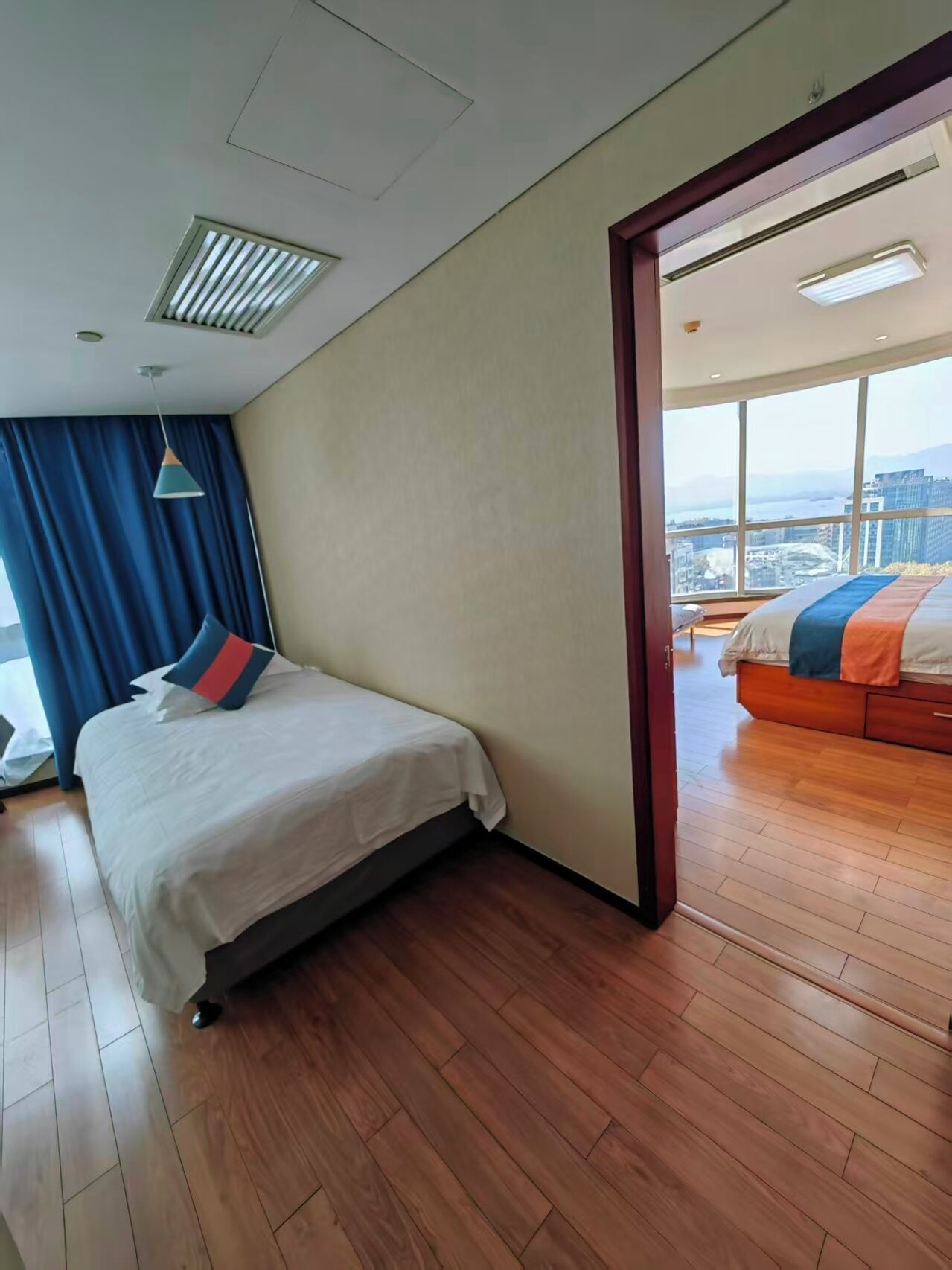 A hotel room with a bed, a view of the city, and a balcony.