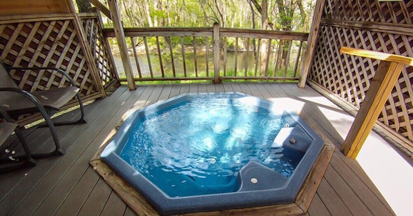 Un bain à remous sur une terrasse en bois, avec vue sur un paysage naturel.