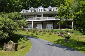 A two-story building with a balcony, surrounded by greenery and a curved driveway. - Bald Mountain House Inn at the Wolf Laurel Resort (Mars Hill)